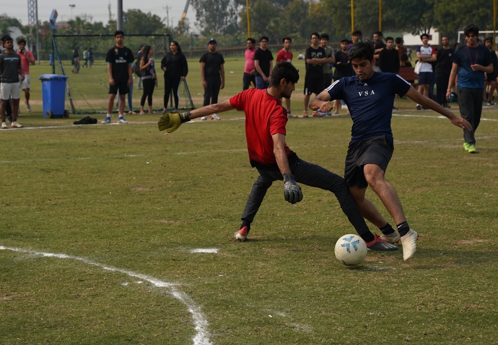 man in red shirt and black shorts playing soccer during daytime