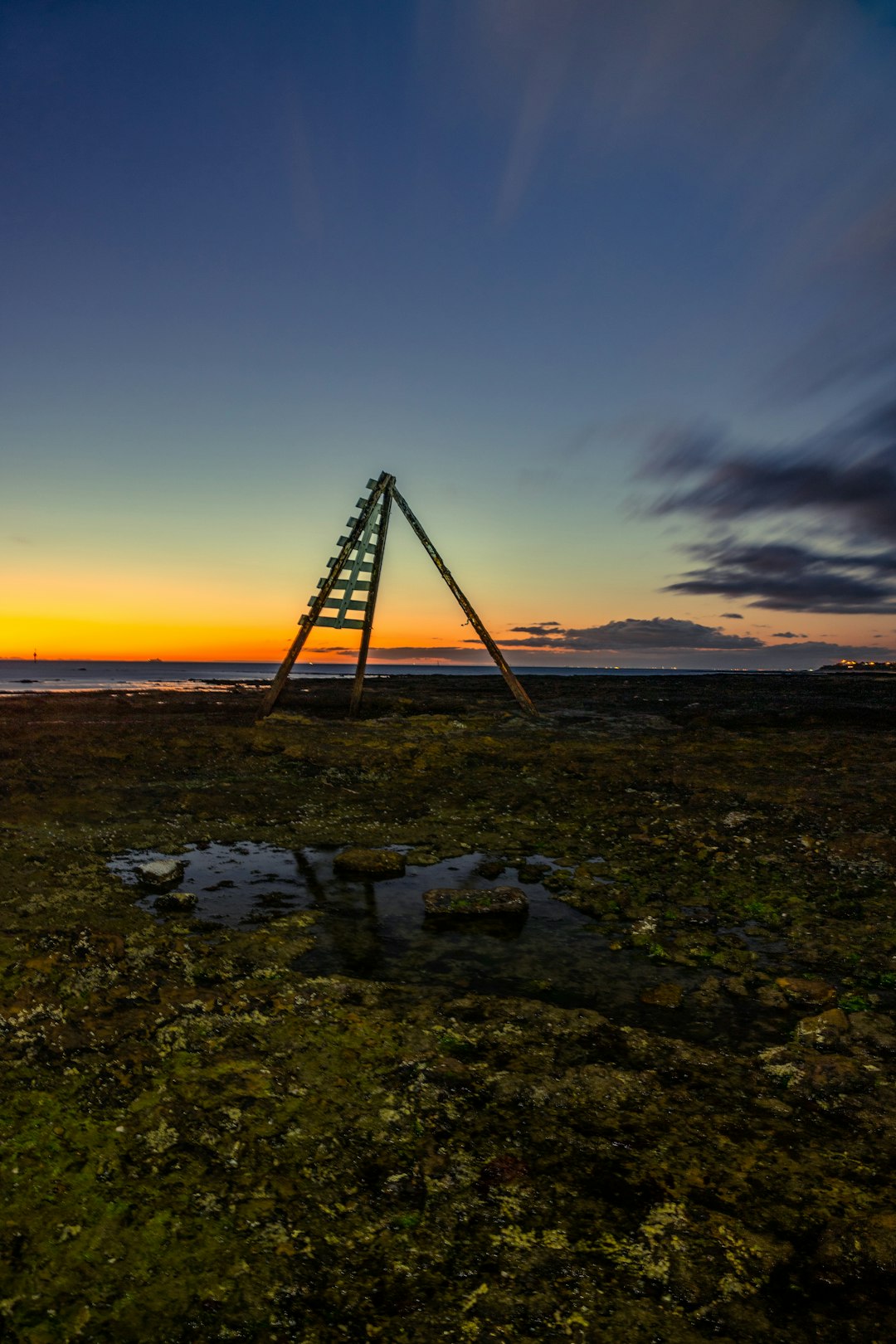 black metal tripod on green grass field during sunset