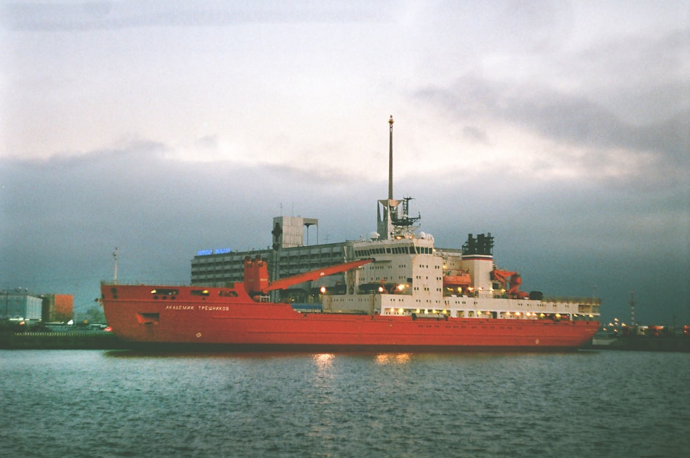 red and white cargo ship on sea under gray sky