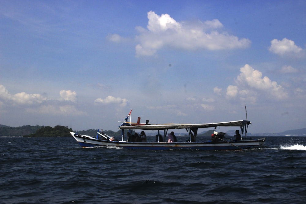 people riding on white and blue boat on sea under blue and white sky during daytime