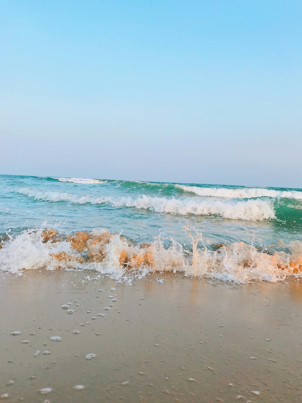 sea waves crashing on shore during daytime