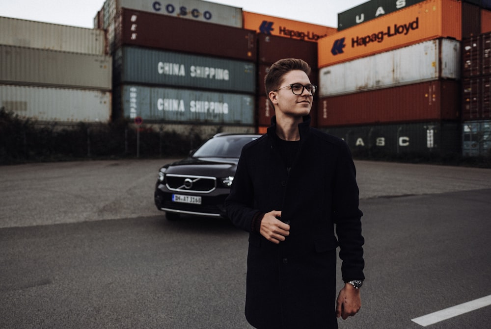 man in black long sleeve shirt standing beside black car