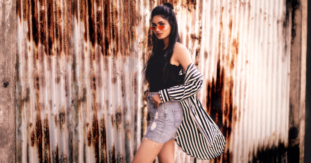 woman in black and white striped long sleeve shirt and blue denim shorts leaning on brown