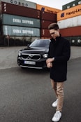 man in black blazer standing beside black mercedes benz car