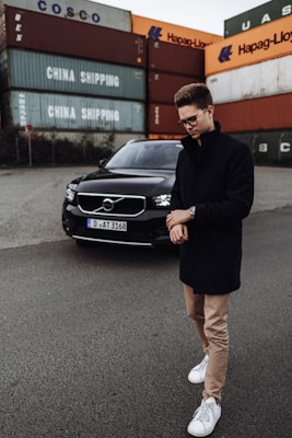 man in black blazer standing beside black mercedes benz car