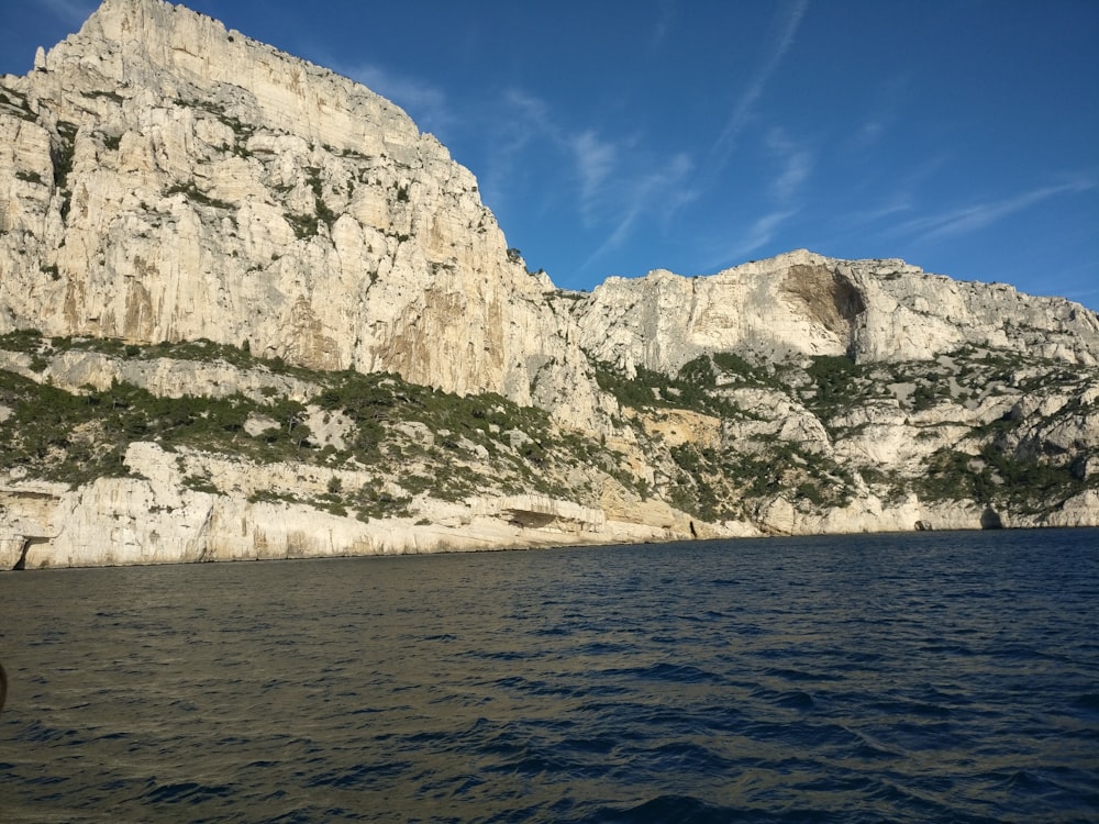 gray rocky mountain beside body of water during daytime