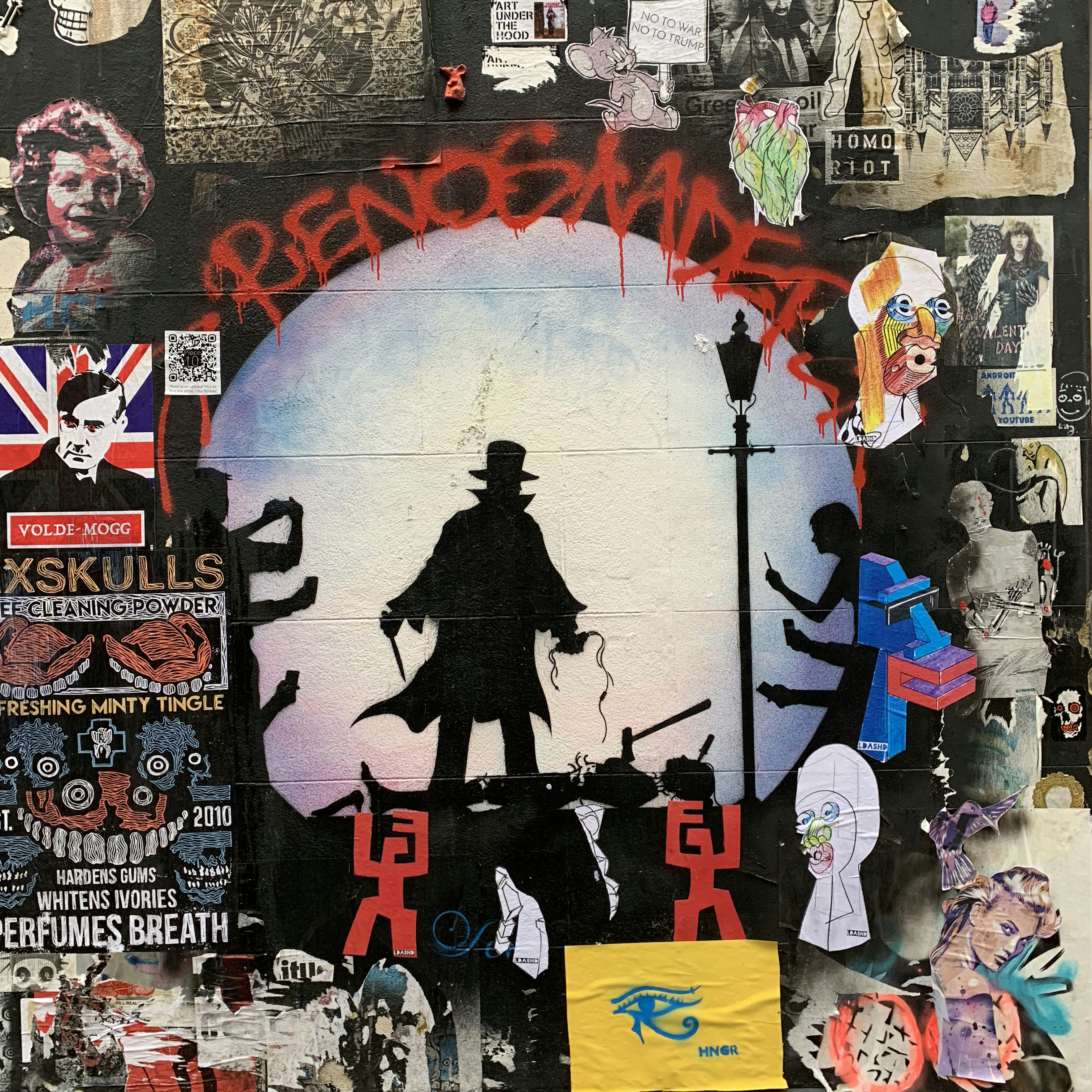 man in black coat standing on the street painting