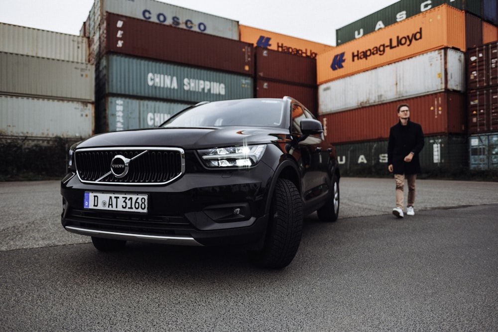 man in black jacket standing beside black car