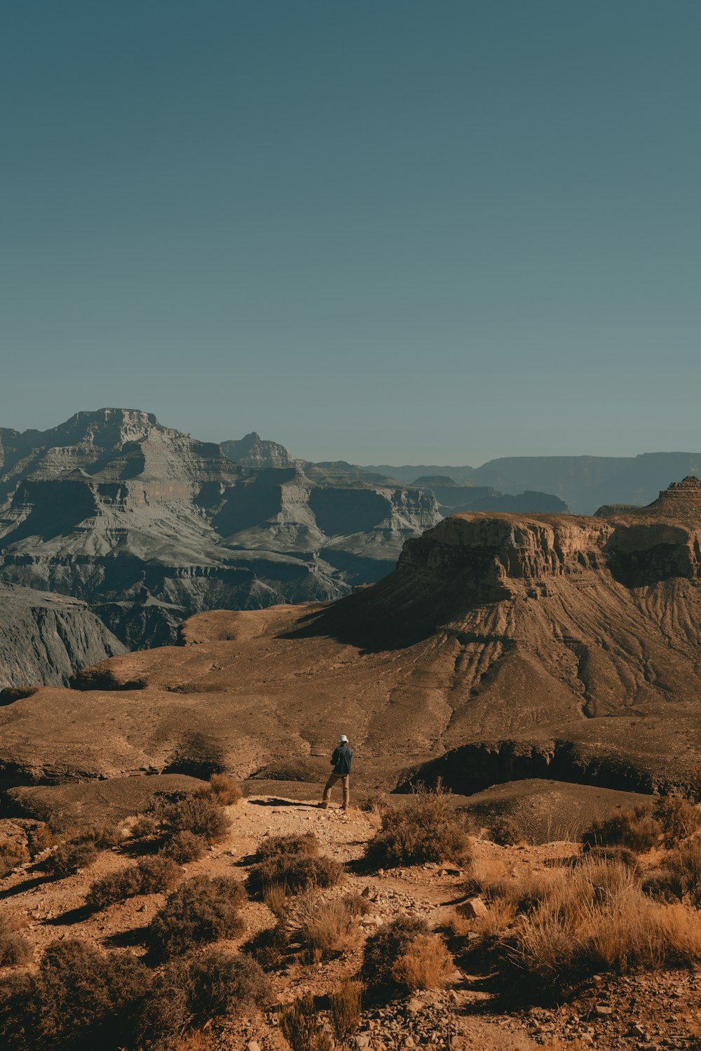 person walking on brown field near brown rocky mountain during daytime