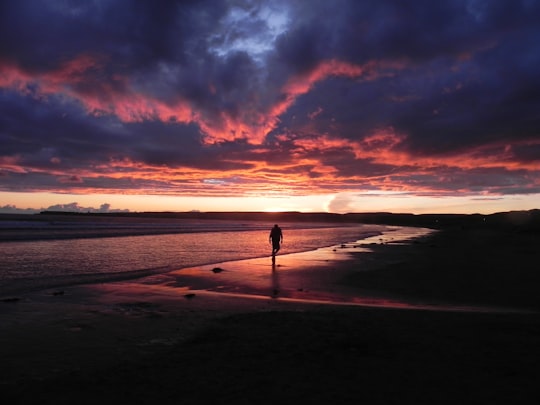 person standing on beach during sunset in Lahinch Ireland