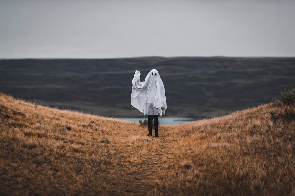 woman in white coat standing on brown grass field during daytime