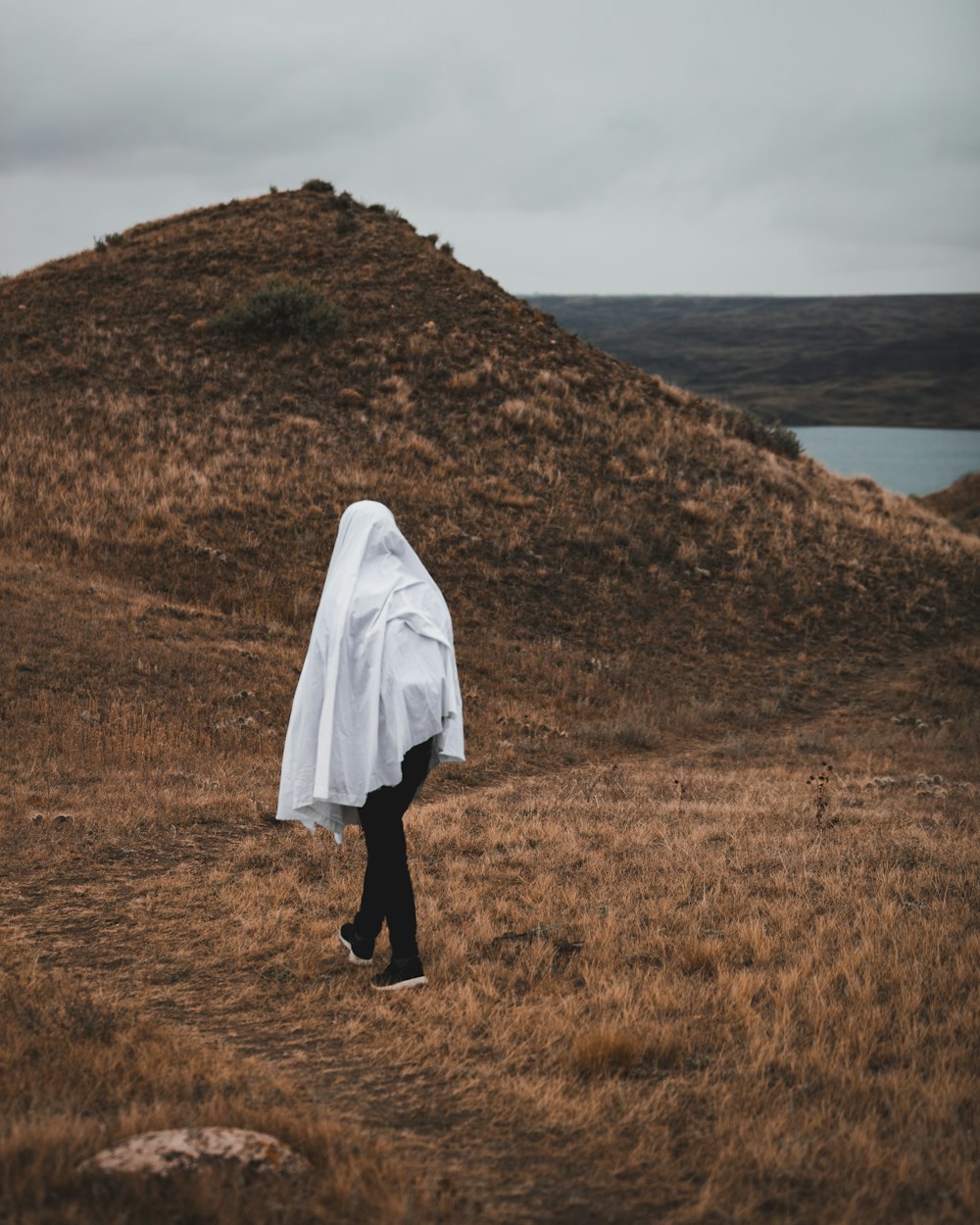 person in white robe standing on brown grass field during daytime