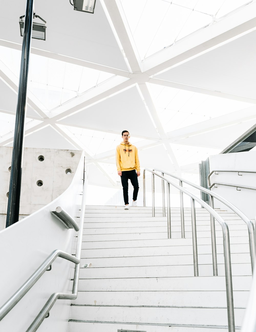 woman in yellow long sleeve shirt and black skirt walking on white staircase