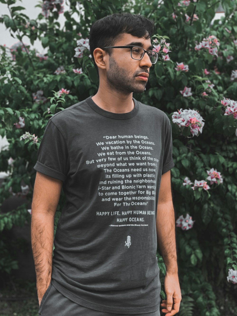 man in black crew neck t-shirt standing beside purple flowers