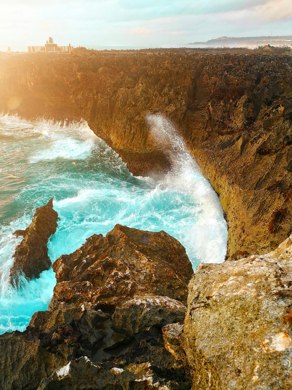 water waves hitting brown rock formation during daytime