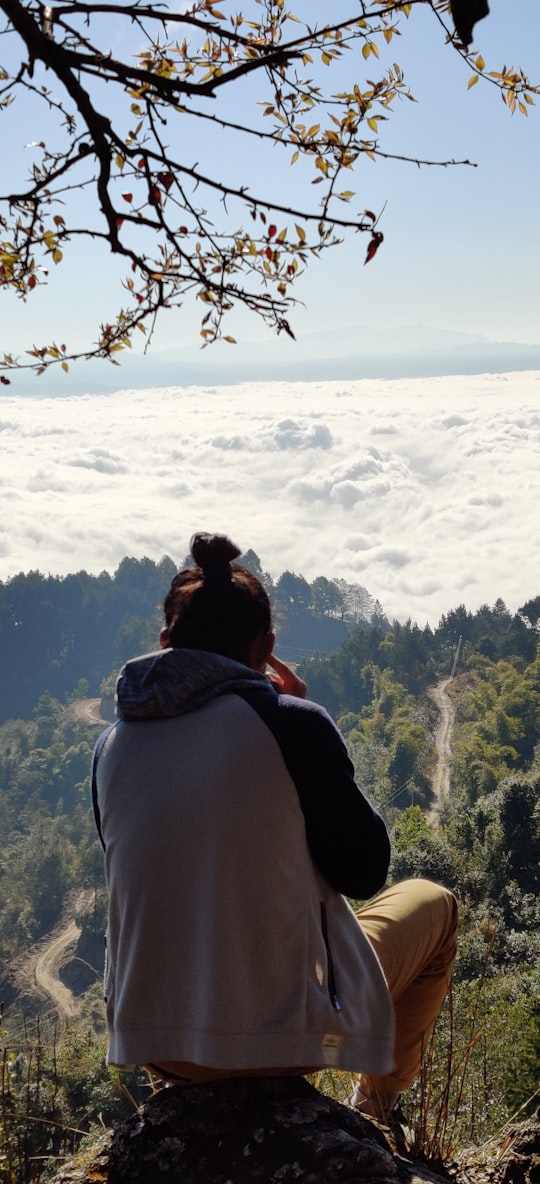 woman in gray hoodie standing on mountain top during daytime in Haibung Nepal