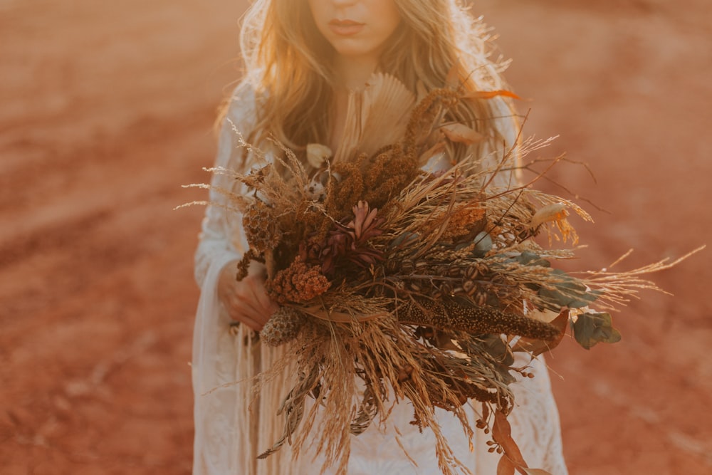 woman in white long sleeve dress holding brown dried plant
