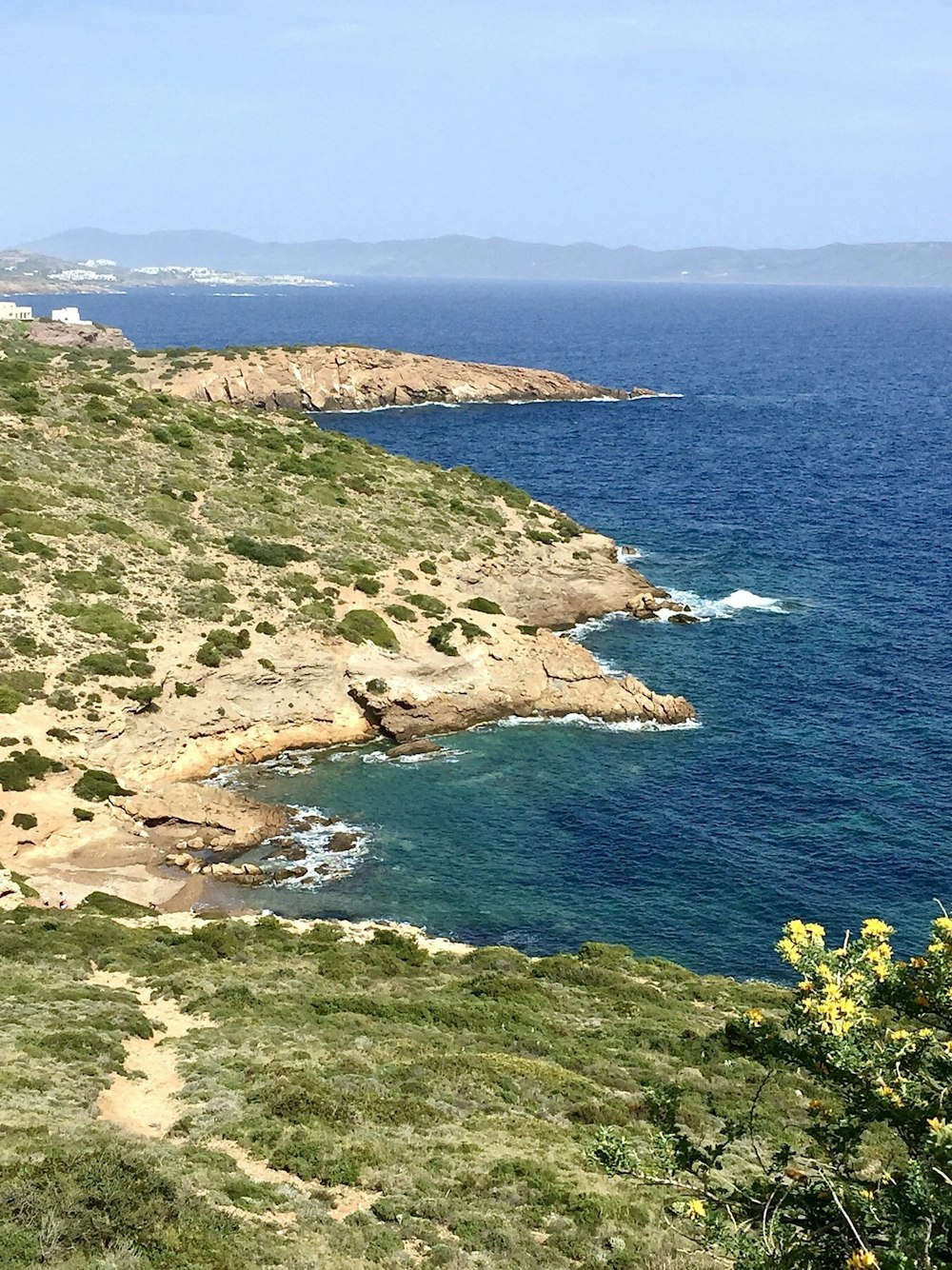 grüner und brauner Berg neben blauem Meer tagsüber