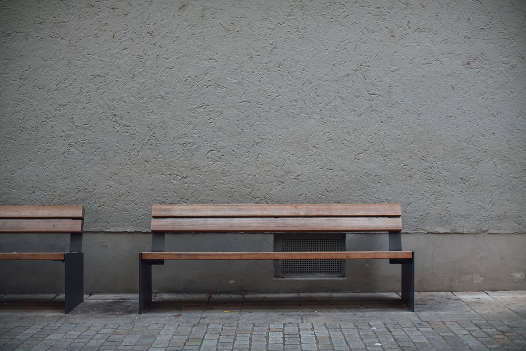 brown wooden bench beside white wall