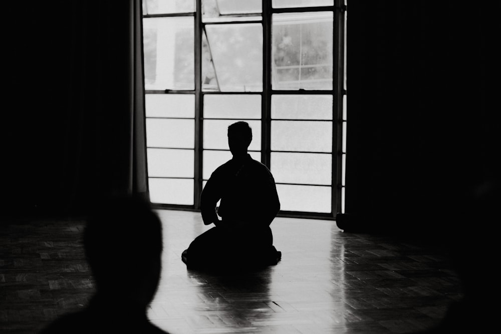 silhouette of man sitting on floor near window