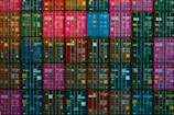 Stacked shipping containers in vibrant colors ready for transport at Sharjah port.