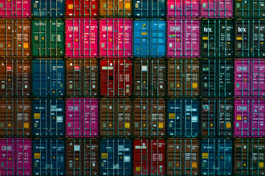 A row of sturdy 20ft and 40ft shipping containers in vibrant colors, neatly arranged at a storage yard.