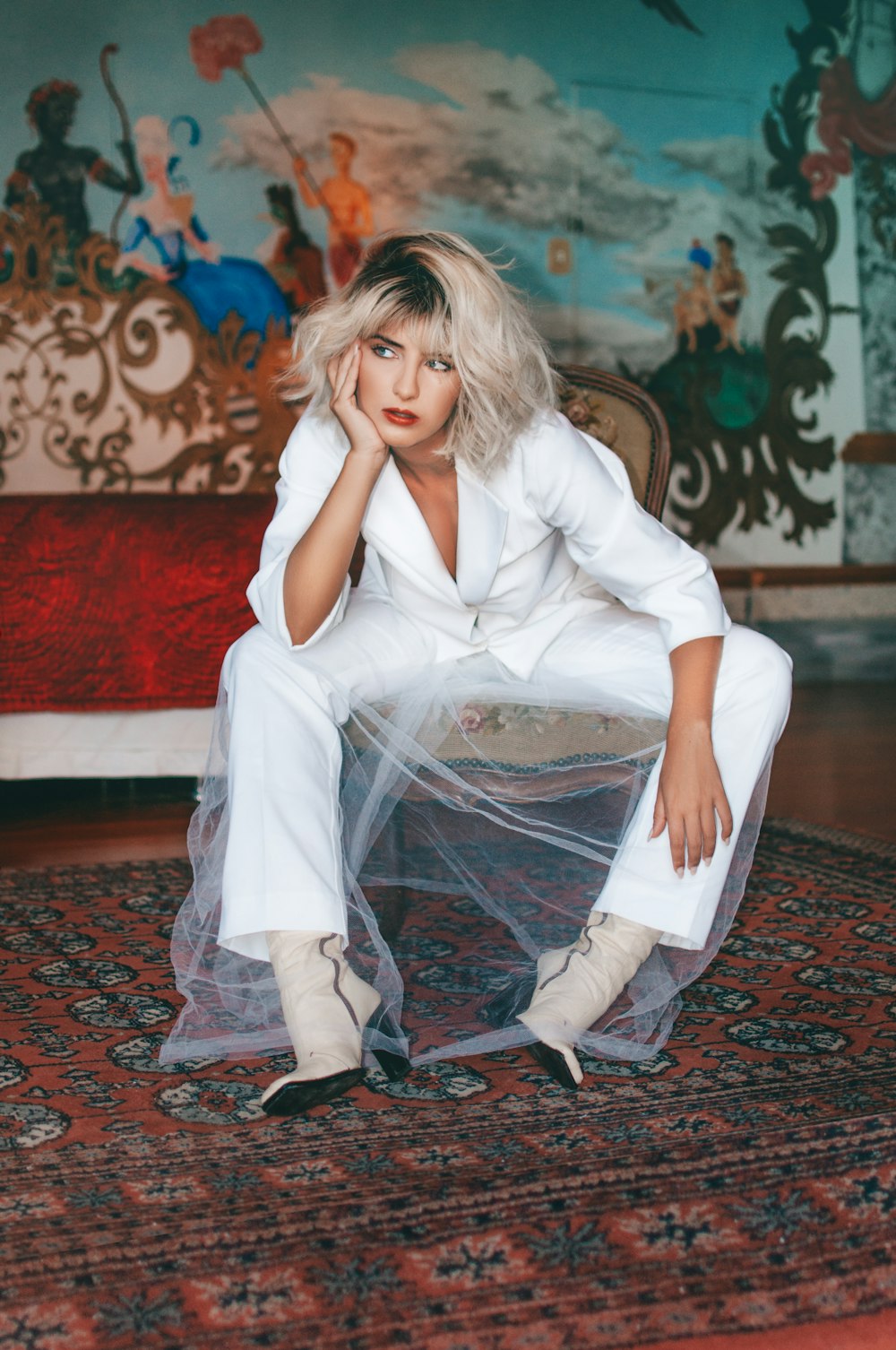 woman in white long sleeve shirt sitting on red and brown carpet