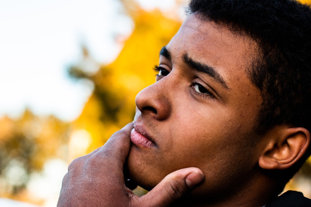 man in black shirt holding his face