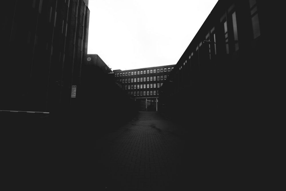 grayscale photo of empty road between high rise buildings