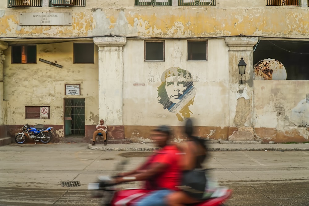 persone sedute sulla panchina vicino all'edificio in cemento beige durante il giorno