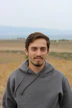 man in gray hoodie standing on field during daytime