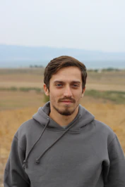 man in gray hoodie standing on field during daytime