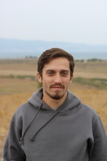 man in gray hoodie standing on field during daytime