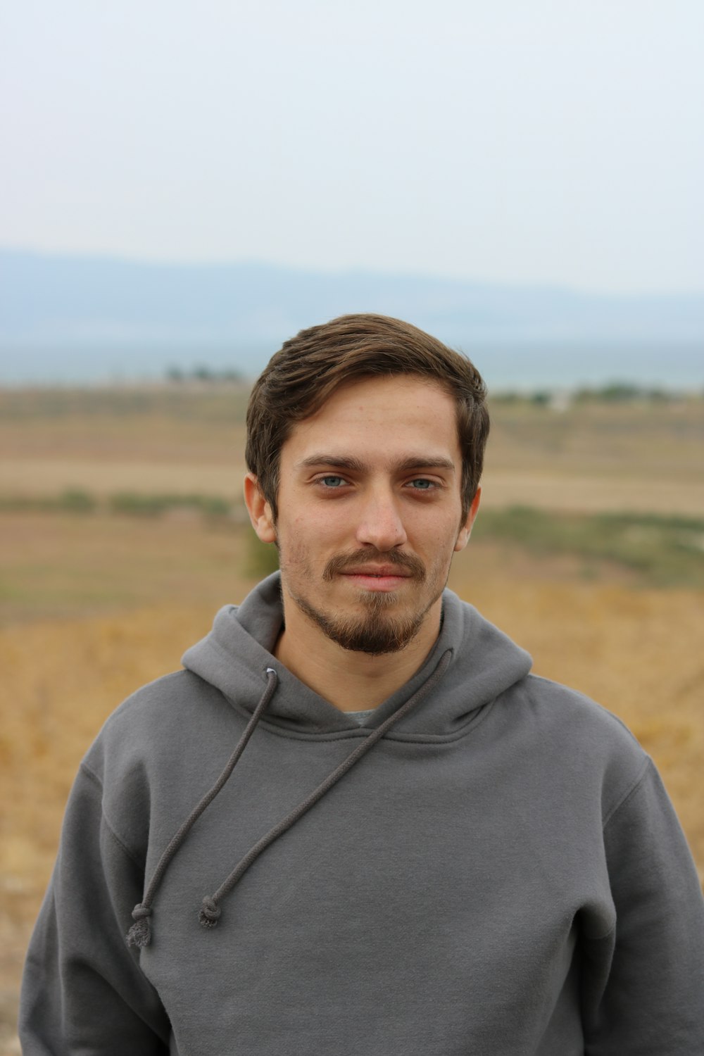 man in gray hoodie standing on field during daytime