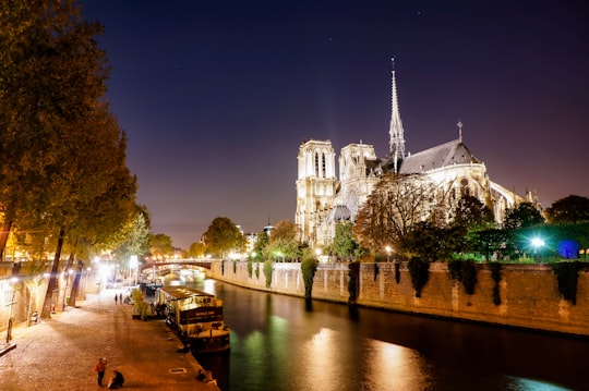 white concrete building near body of water during night time in Cathédrale Notre-Dame de Paris France