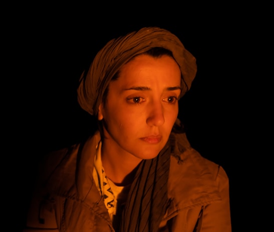 A woman gazing thoughtfully into the distance with a gentle smile.