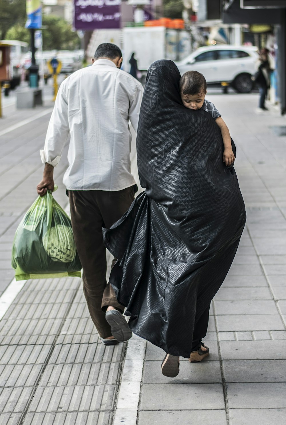 mujer con vestido negro sosteniendo una bolsa de plástico verde