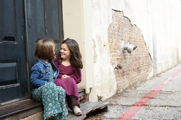 2 girls sitting on concrete floor
