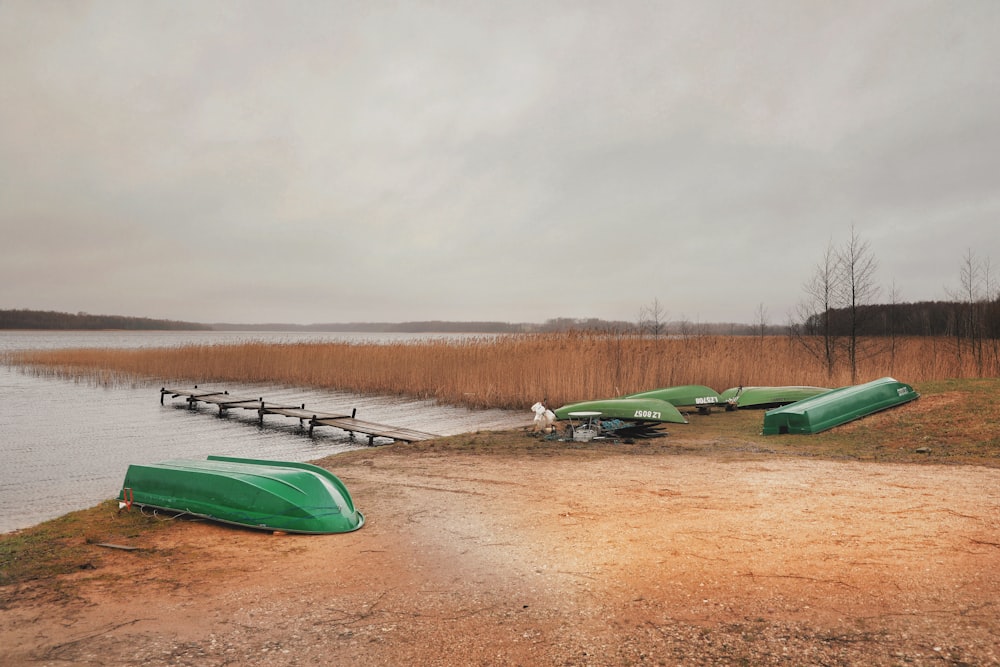 green and white boats on brown sand under gray sky