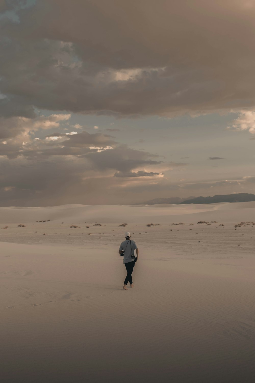 man in white jacket walking on desert during daytime