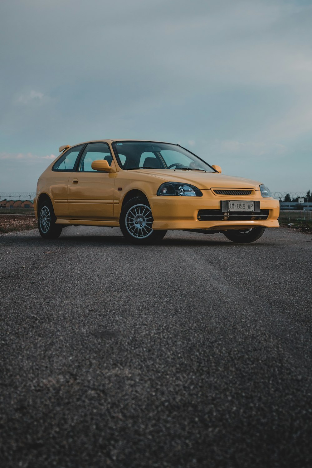 yellow sedan on gray asphalt road during daytime