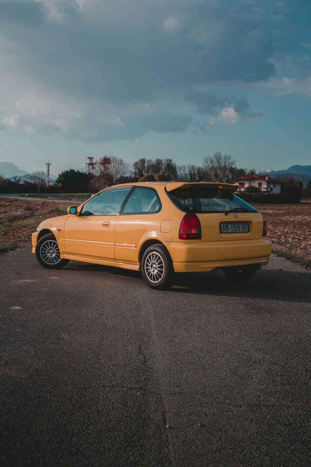 yellow sedan on gray asphalt road during daytime