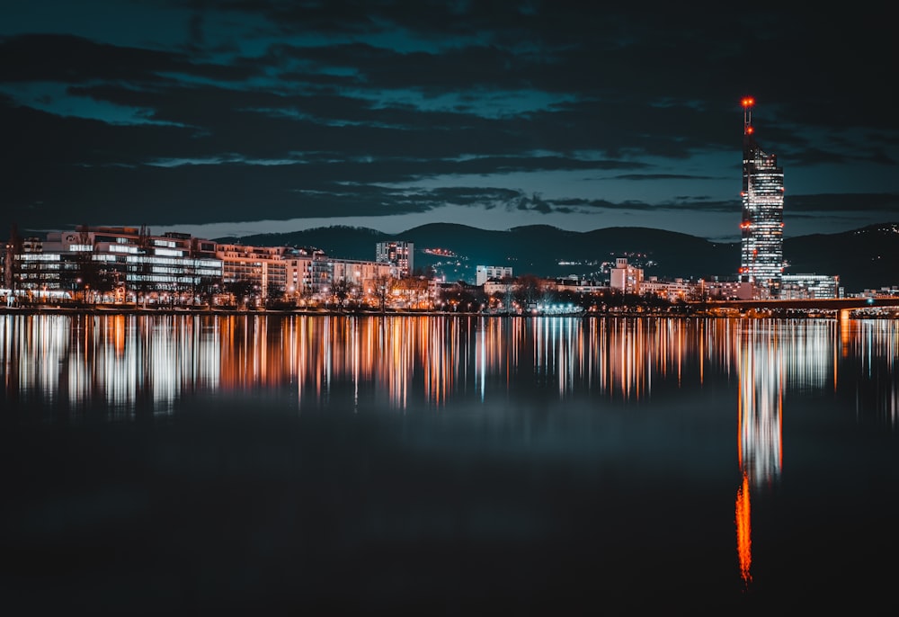 city skyline across body of water during night time