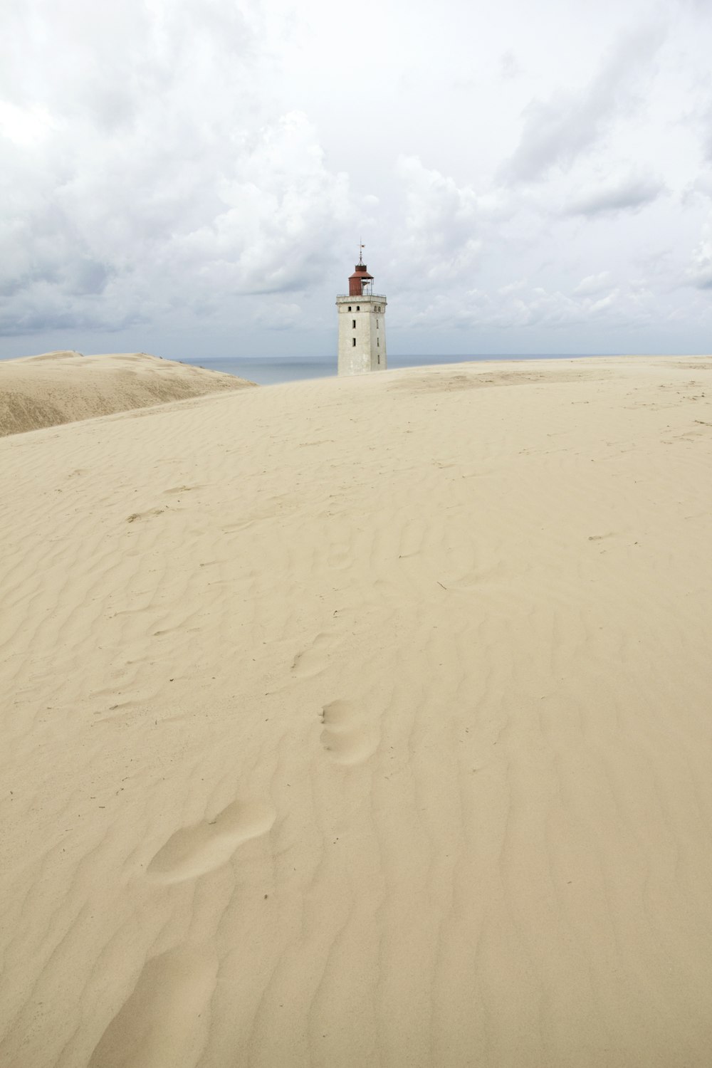 white and red lighthouse on white sand during daytime