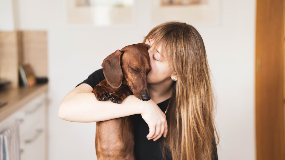 woman in black tank top hugging brown short coated dog