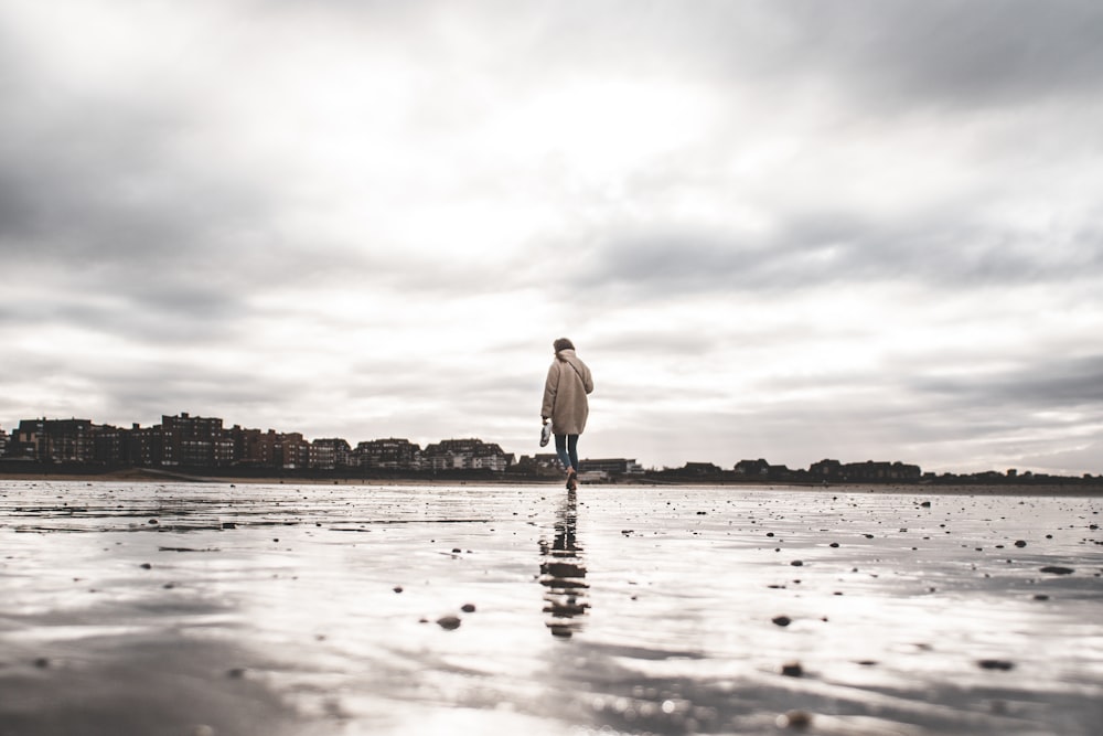 homme en chemise blanche et jean bleu debout sur la plage pendant la journée