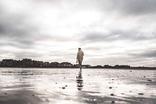 man in white dress shirt and blue denim jeans standing on beach during daytime in Cabourg France