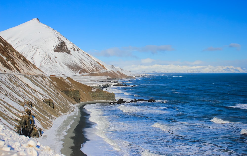 brown and white mountain beside blue sea under blue sky during daytime