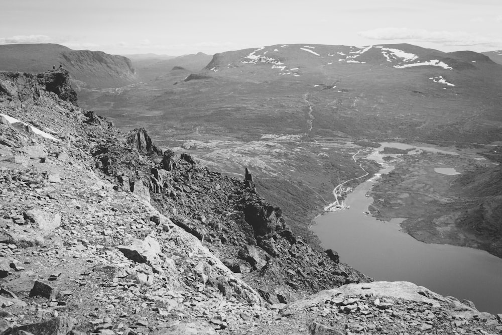 grayscale photo of river between mountains