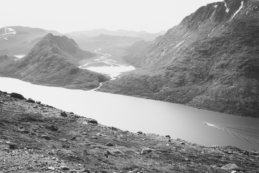 grayscale photo of lake between mountains